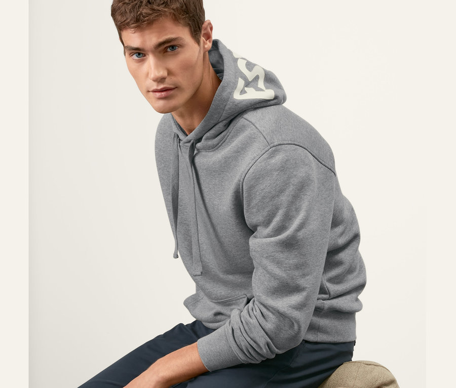 Un homme est assis sur une chaise et porte un sweat-shirt à capuche gris.