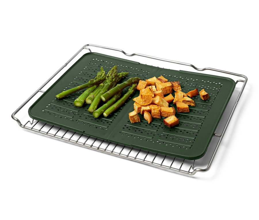 Asperges et patates douces coupées sur une plaque de four en silicone placée sur une grille.