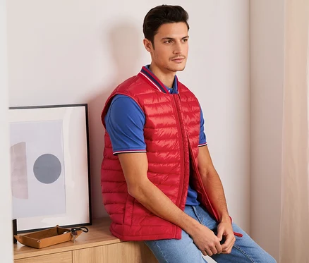 Un homme est assis et porte un gilet surpiqué rouge.