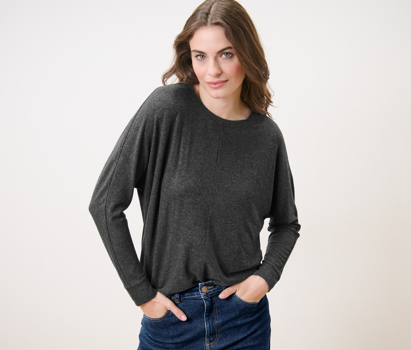 Femme posant en pull manches chauve-souris et jean.