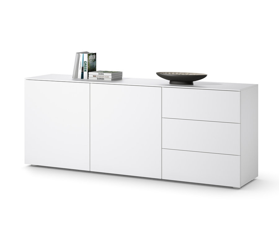 Buffet blanc avec trois tiroirs et des portes, sur lequel reposent des livres et un bol.