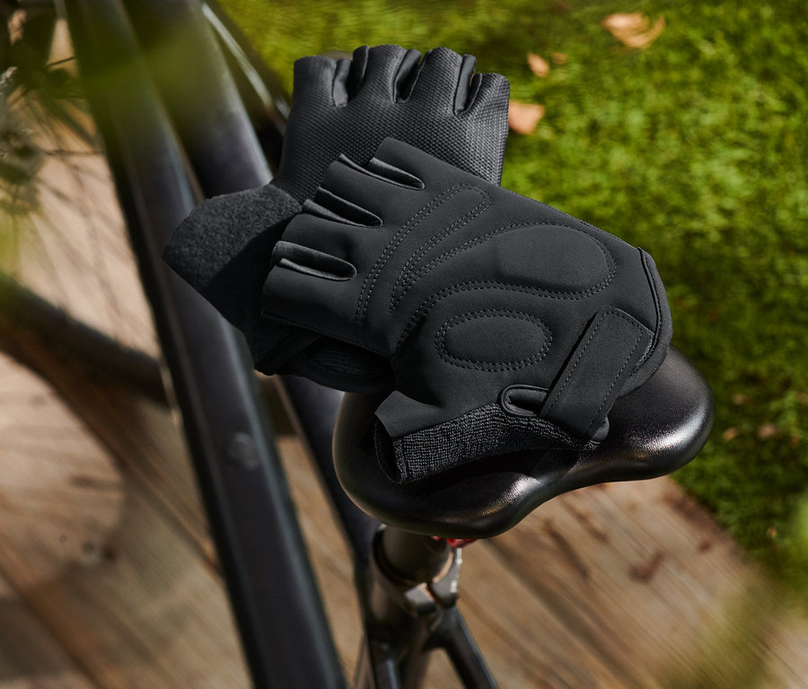 Des gants de vélo noirs sont posés sur une selle de vélo.