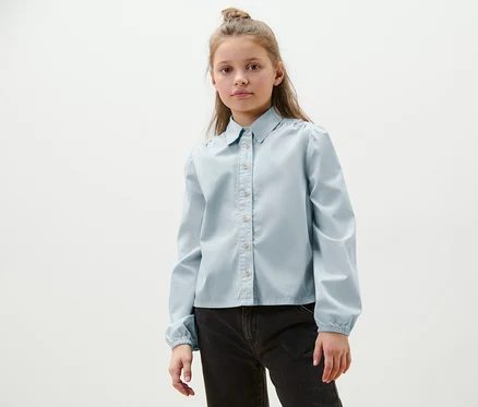 Portrait d'une fille portant une blouse en jean pour enfant.