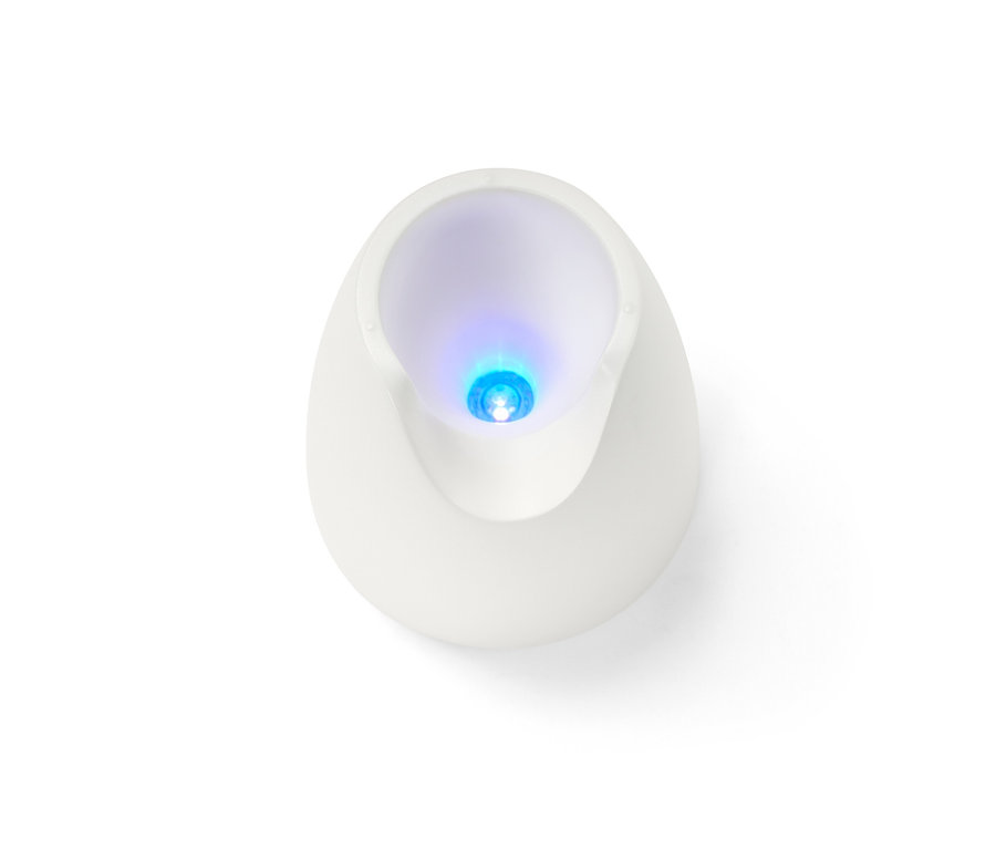 Gros plan vu de dessus d'une lampe UV blanche d'un kit manucure-pédicure 5 en 1, illuminant en bleu.