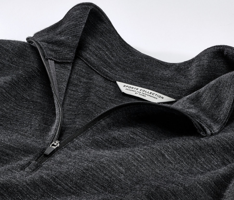 Gros plan sur un t-shirt technique gris avec de la laine certifiée RWS et une fermeture éclair.