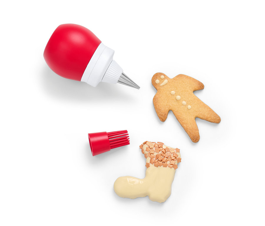 Une bouteille décorative 2 en 1 rouge avec embout et pinceau à côté de biscuits sur fond blanc.