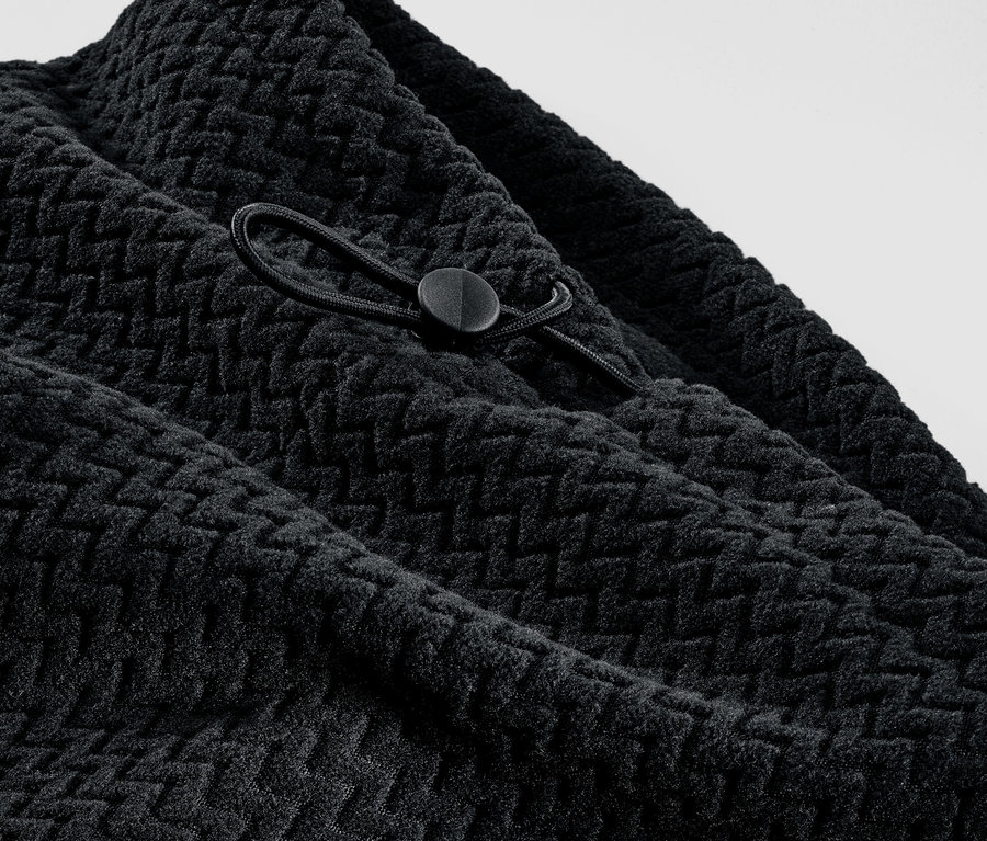 Gros plan sur un col en polaire noir texturé avec cordon de serrage.