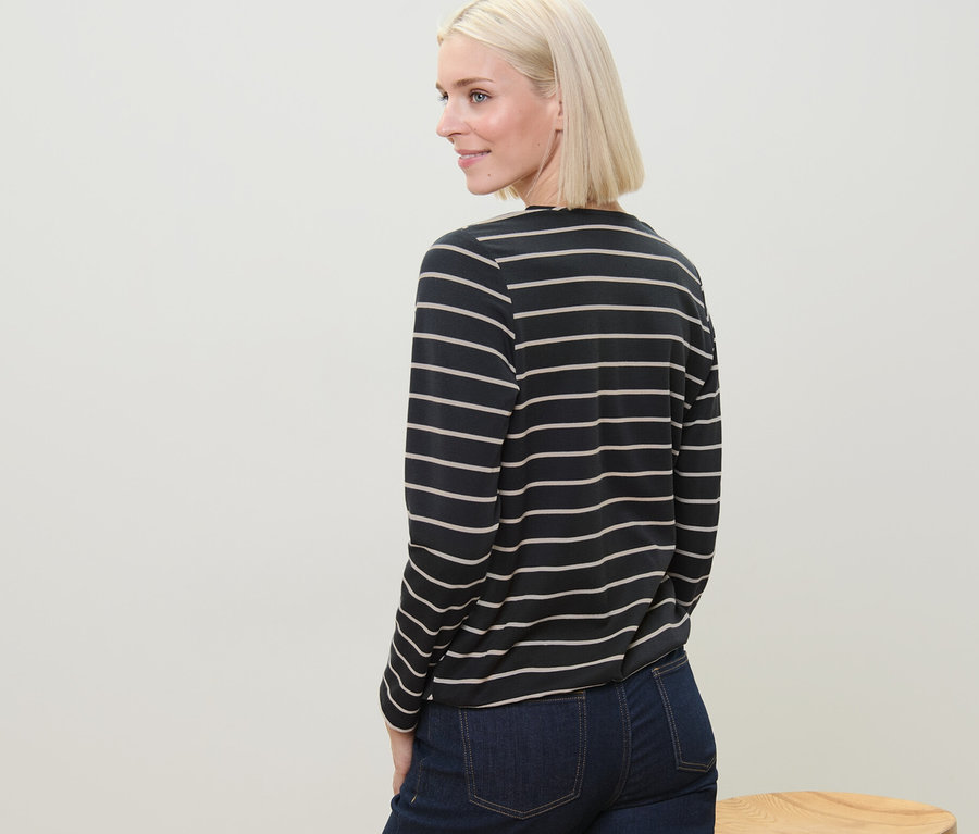 Blonde regardant par-dessus son épaule portant une blouse rayée en modal mélangé et un jean.