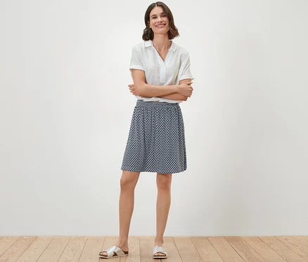 Une femme se tient debout, les bras croisés, portant une robe en jersey imprimée.