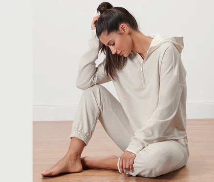 Femme assise par terre portant un pull molletonné.