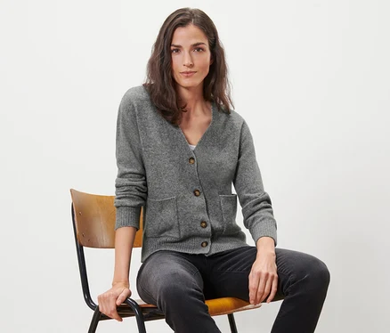 Femme assise sur une chaise portant une jaquette en maille avec de la laine, gris chiné.