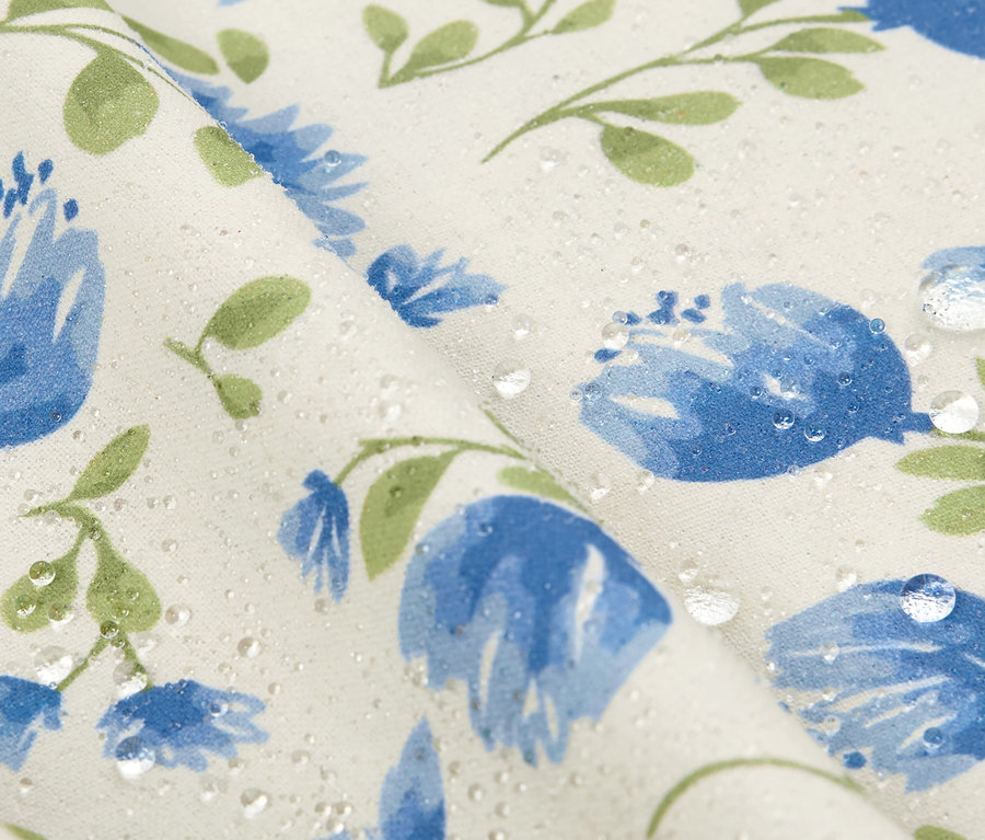 Gros plan sur une nappe lavable (env. 90 x 90 cm) avec des fleurs bleues et des gouttes d'eau.