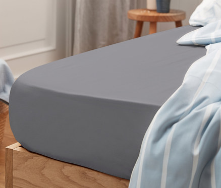 Drap-housse en jersey gris de taille standard sur un lit.