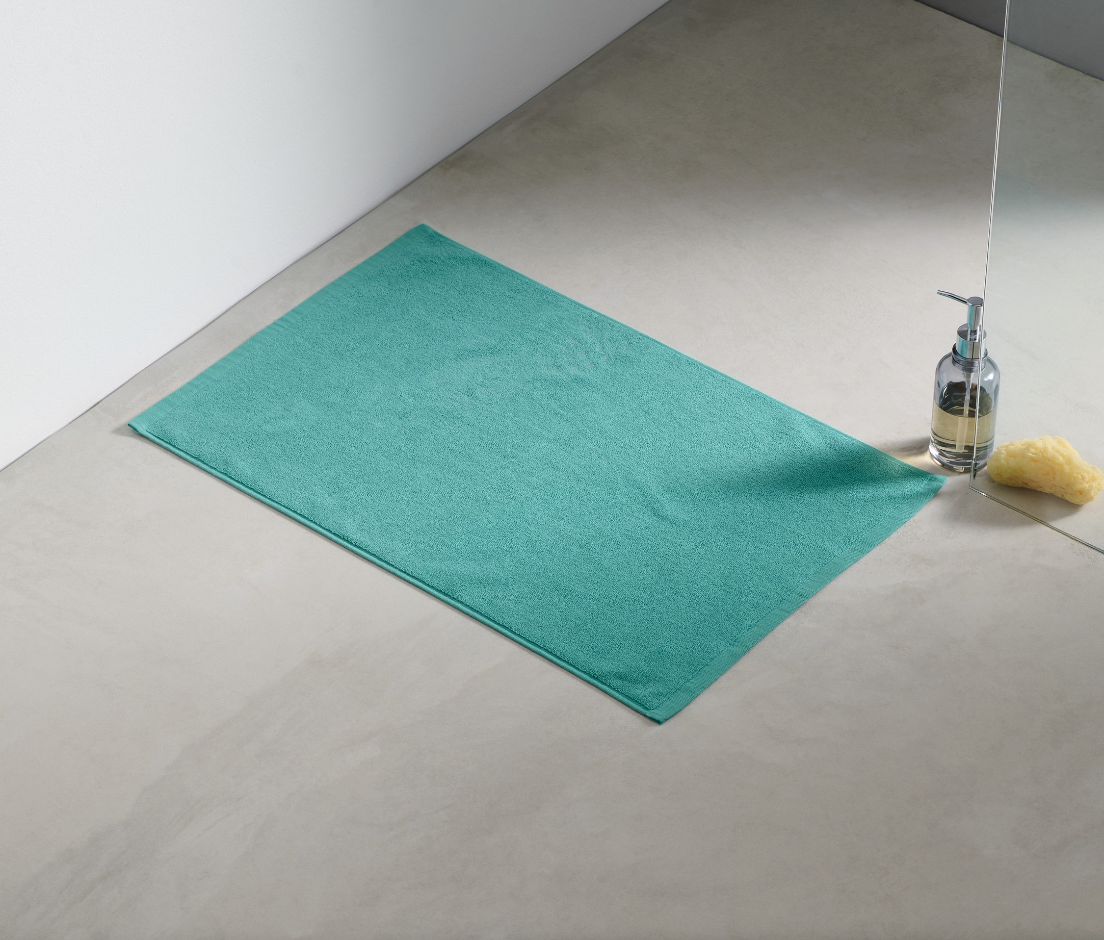 Un tapis de douche turquoise est posé sur le sol à côté d'une douche.