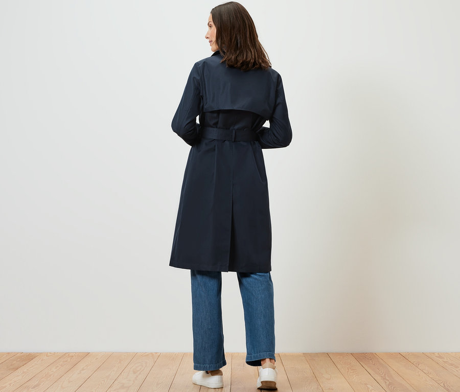 Femme portant un trench-coat bleu foncé.