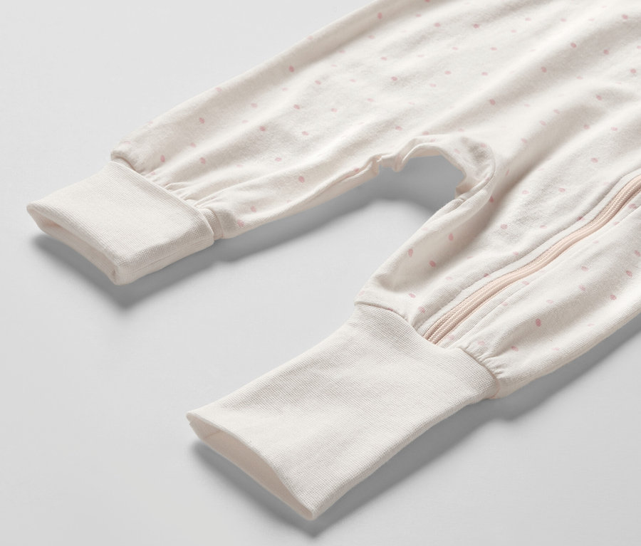 Gros plan sur un pyjama pour bébé avec des points roses et une fermeture éclair. Produit : 3 pyjamas pour bébé, princesse.