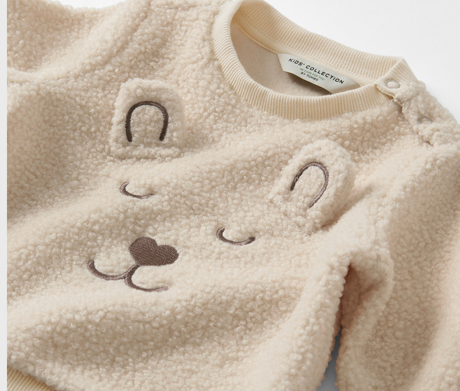 Gros plan sur un sweat-shirt nounours pour enfant avec un visage d'ours.