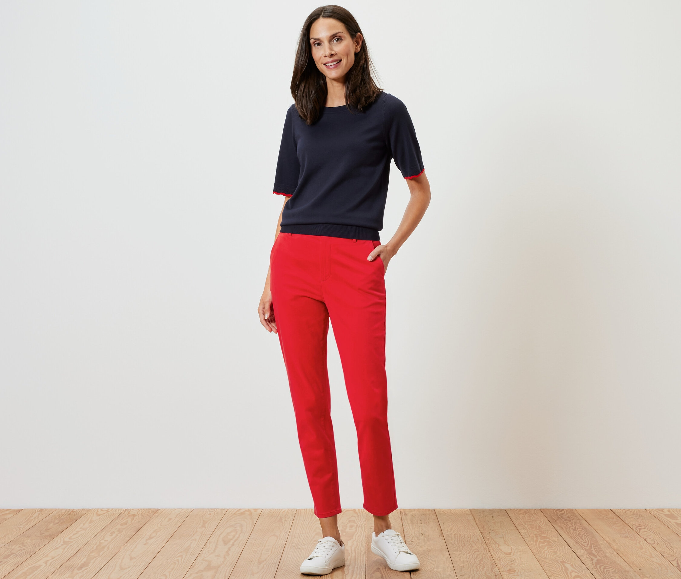Femme posant en pantalon chino rouge et haut bleu marine.