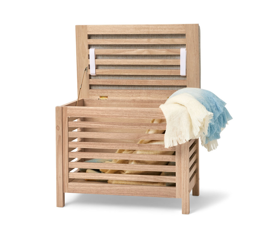 Coffre en bois massif ouvert avec coussin et une couverture jetée dessus.
