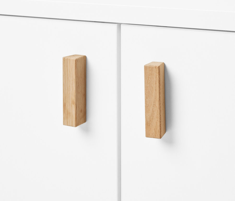 Gros plan d'un meuble sous-vasque blanc avec deux portes et des poignées en bois.