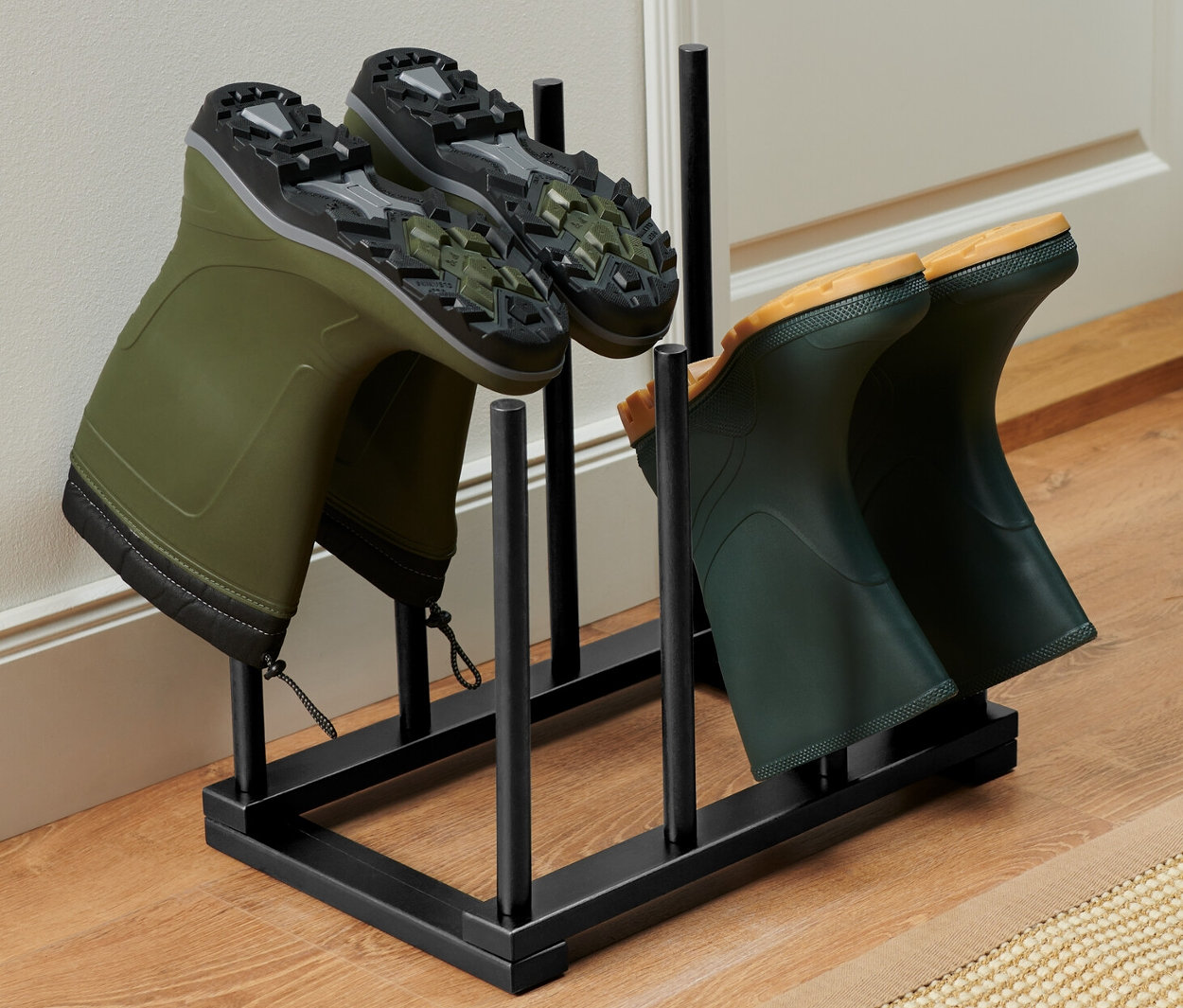 Deux paires de bottes en caoutchouc vertes dans un porte-bottes.