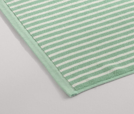 Un tapis de douche vert est posé sur le sol à côté d'une douche.