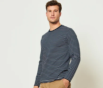Un homme pose et porte l'un des 2 t-shirts manches longues de l'ensemble.