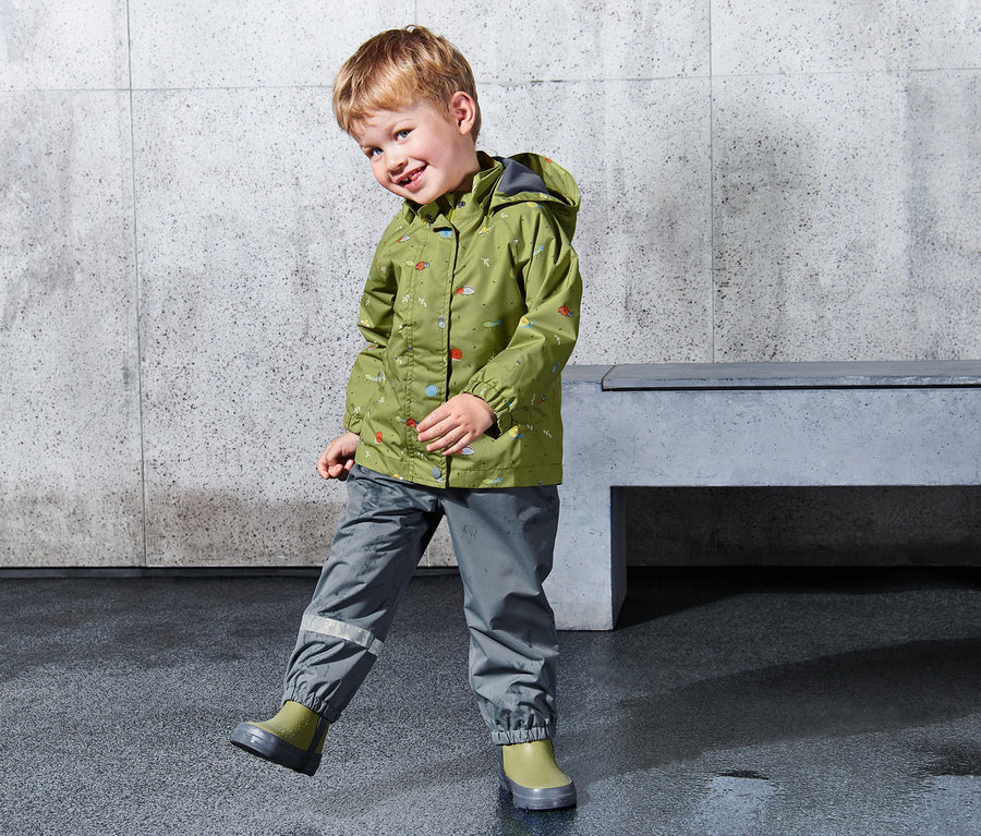 Garçon portant une veste de pluie verte pour enfant avec capuche.