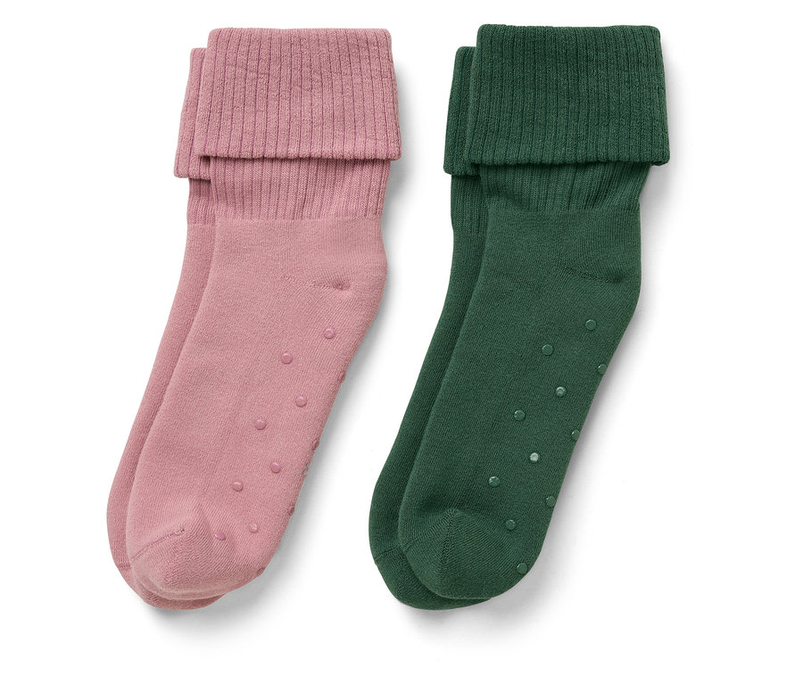 Deux paires de chaussettes : une paire rose, une paire verte. Les deux ont un bord replié et des points antidérapants.