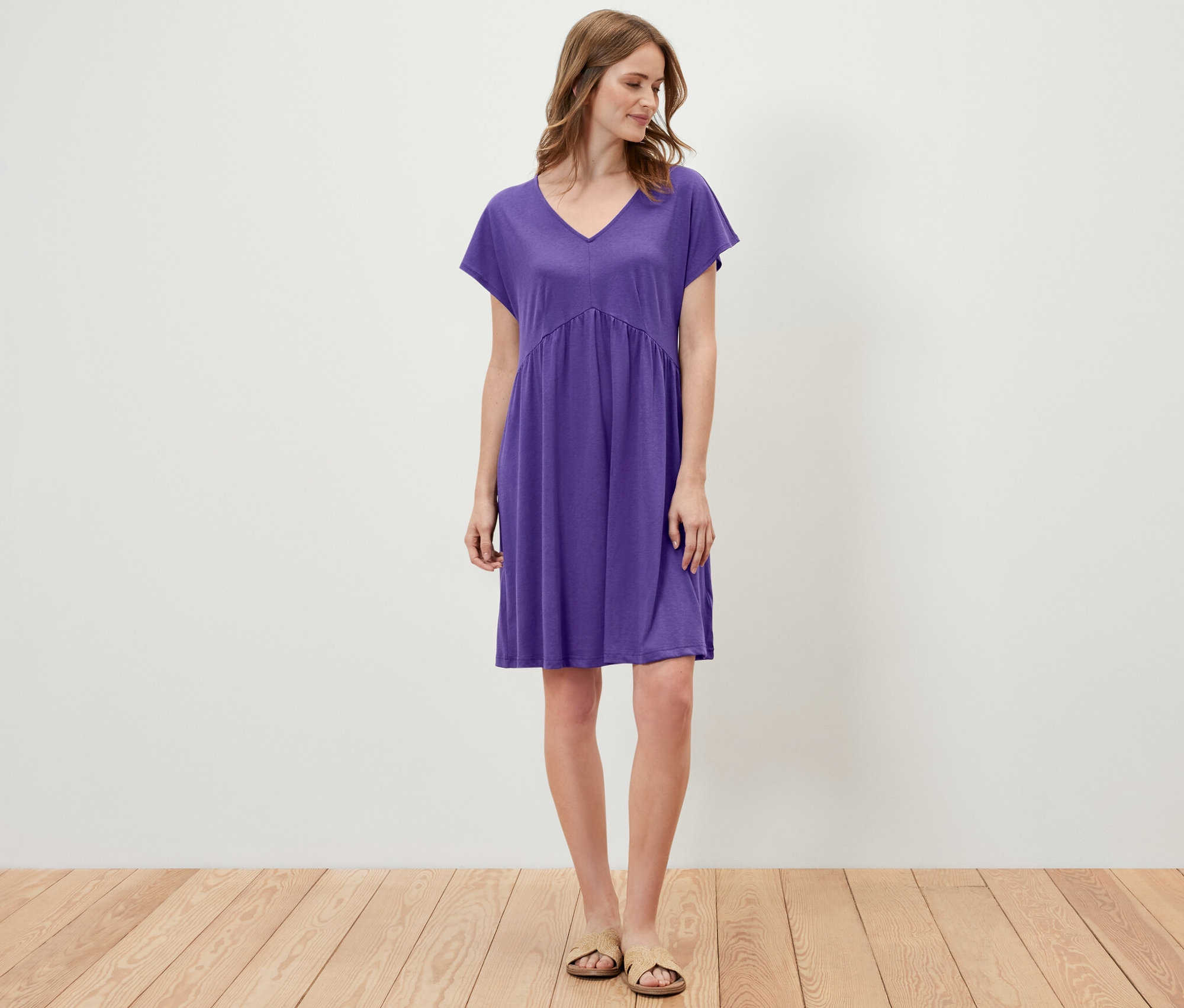Une femme debout portant une robe en jersey violette.