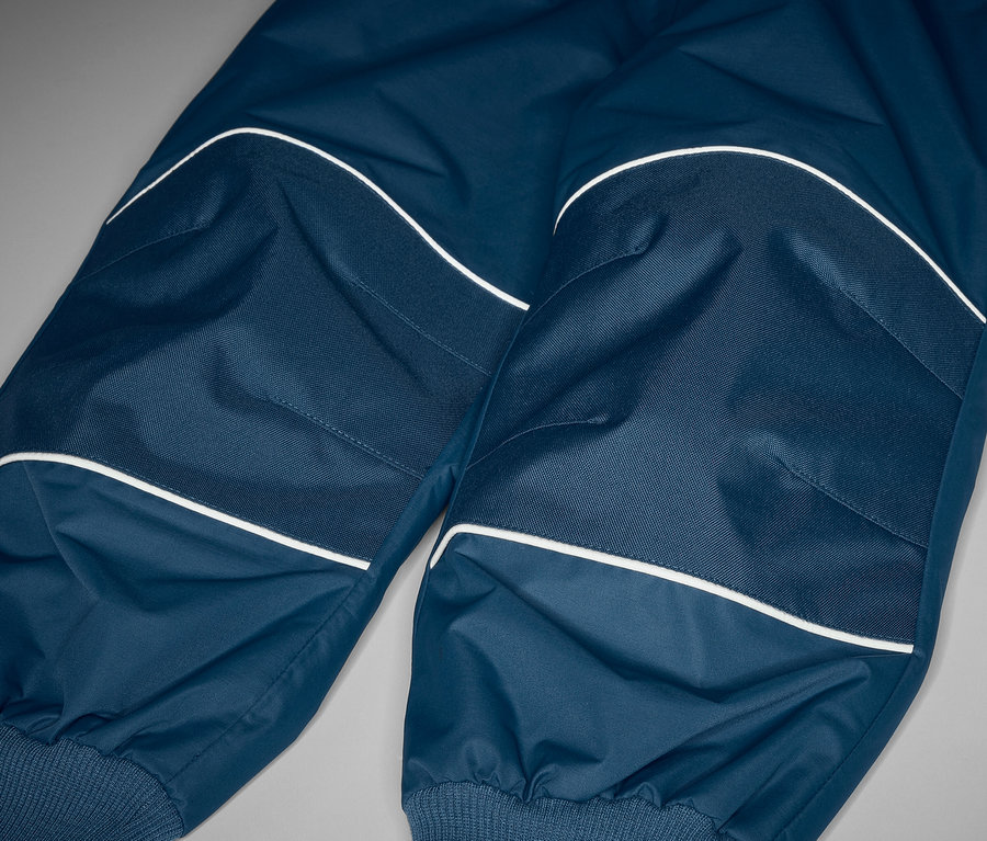 Gros plan sur un pantalon de pluie évolutif pour enfant avec des éléments réfléchissants.