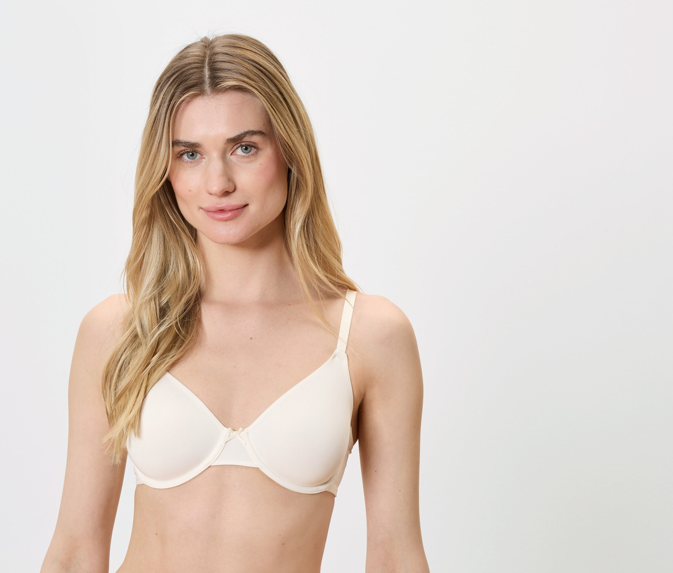 Une femme blonde aux yeux bleus porte un soutien-gorge couleur chair.