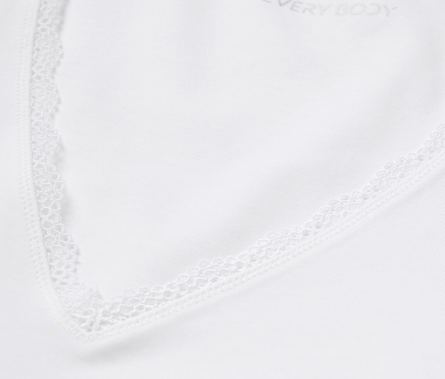 Détail d'un haut blanc avec bordure en dentelle.