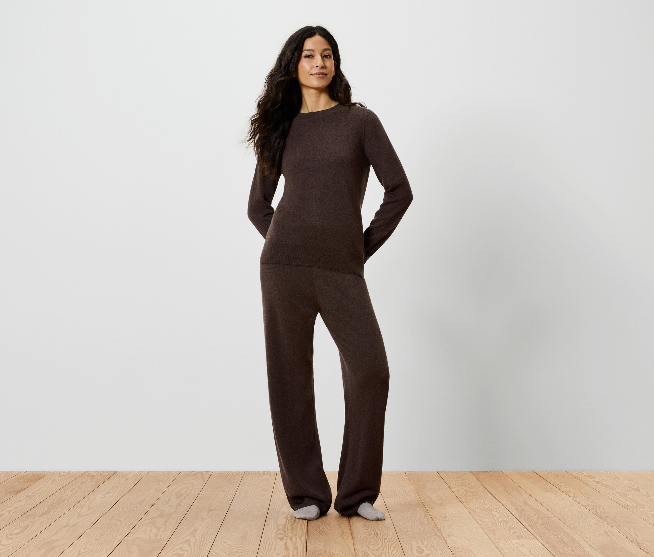 Femme posant en pull et pantalon marron.