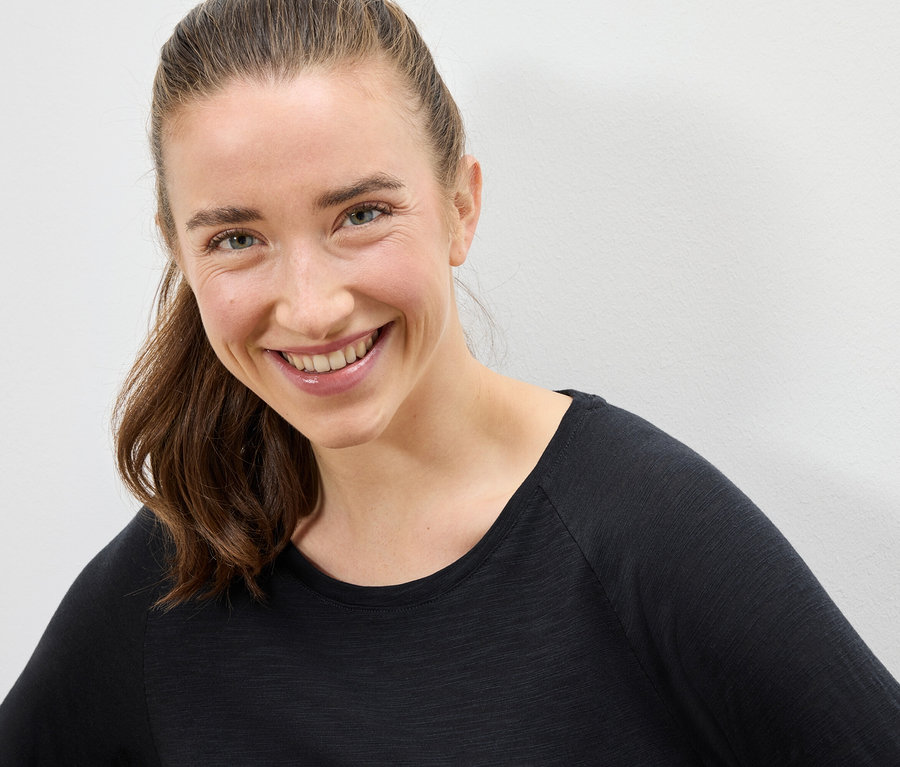 Portrait d'une femme souriante aux cheveux bruns, portant un t-shirt noir.