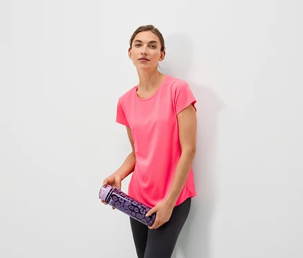 Une femme tenant une bouteille d'eau violette à motifs floraux, portant un t-shirt rose et un legging gris.