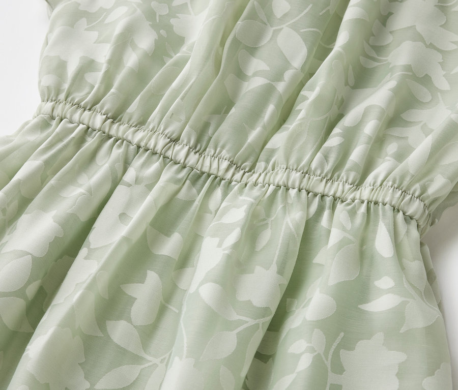 Gros plan d'une robe pour enfant avec un motif de feuilles et une taille élastique.