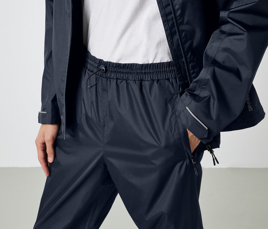 Une personne porte un pantalon et une veste imperméables bleu marine.