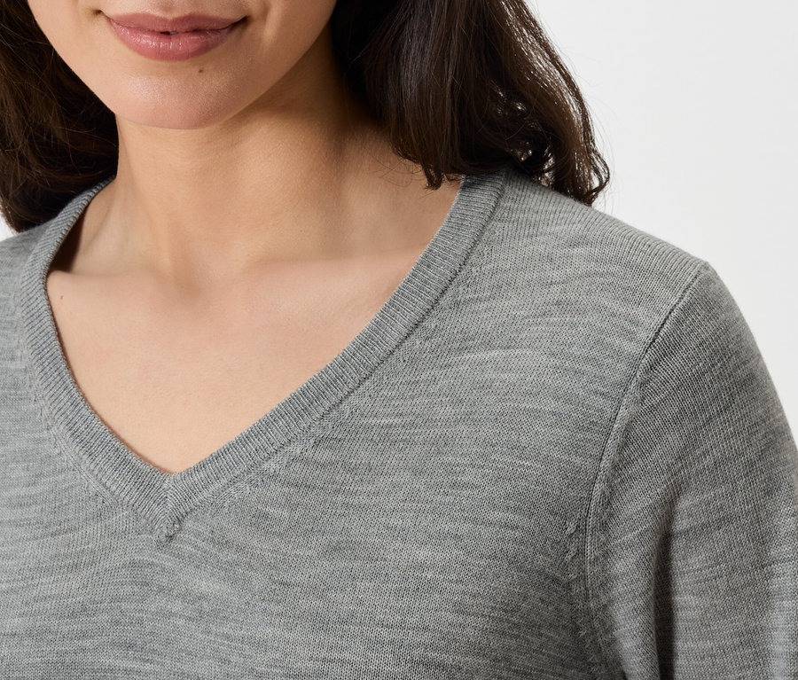 Haut du corps d'une femme portant un pull gris à col en V.