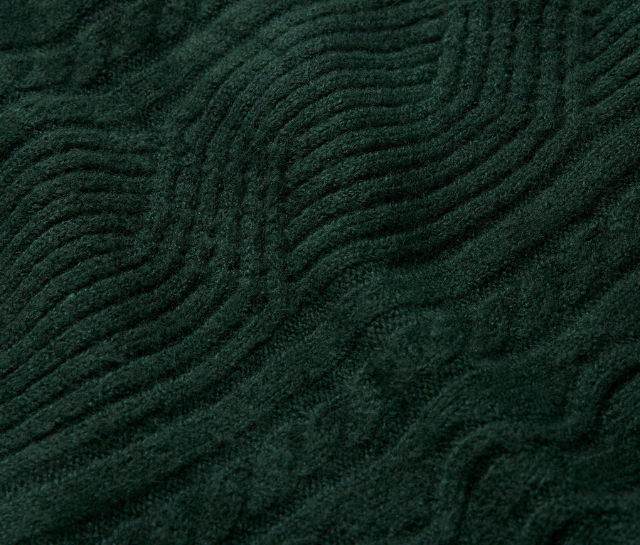 Gros plan d'un motif tricoté vert foncé avec des vagues en relief.