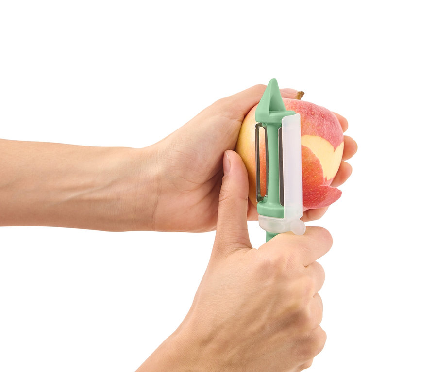 Des mains épluchent une pomme avec un éplucheur universel 2 en 1.