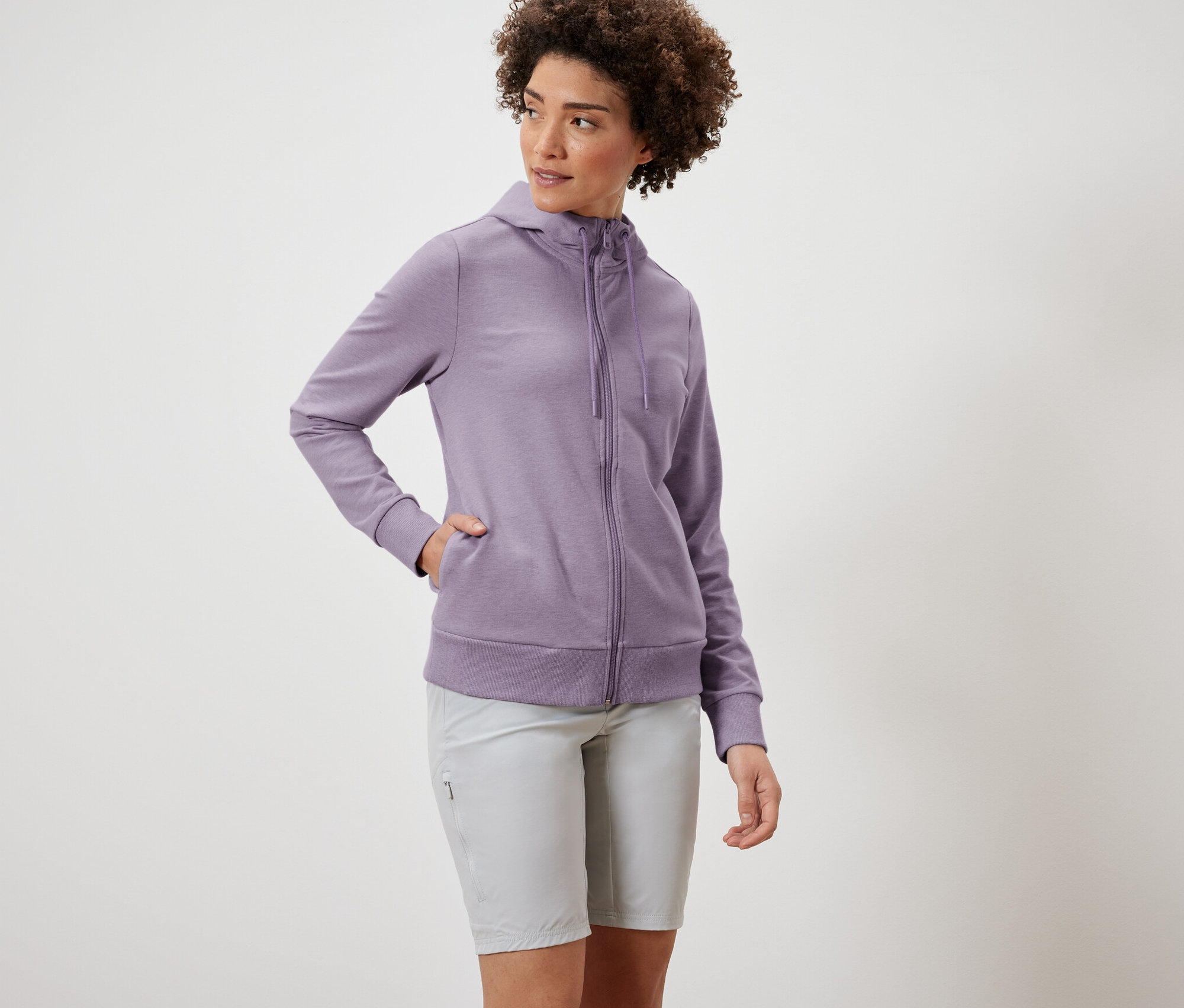 Femme portant une veste molletonnée violette et un short gris.