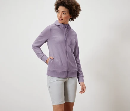 Femme portant une veste molletonnée violette et un short gris.