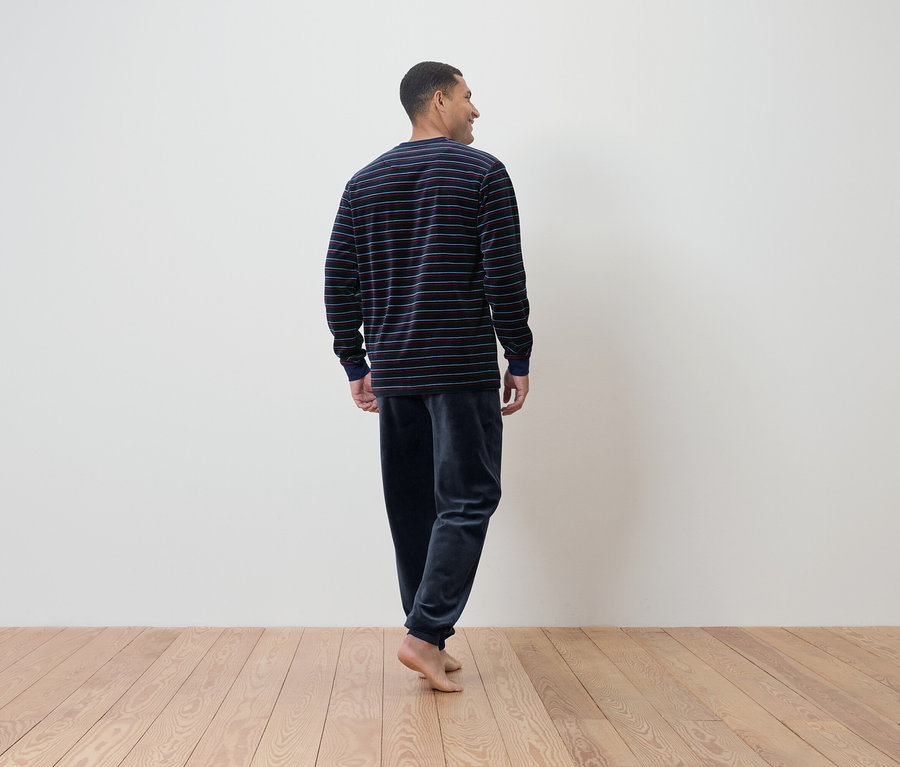 Homme en pyjama rayé, vu de dos.