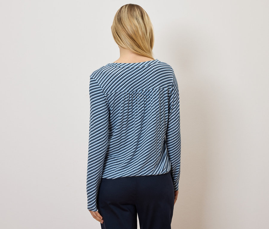 Vue de dos d'une femme blonde portant un haut rayé bleu et blanc et un pantalon bleu foncé.