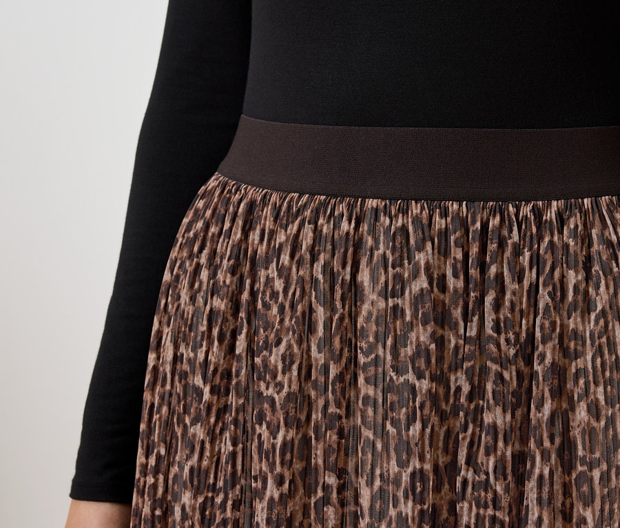 Gros plan d'une jupe pour femme avec un motif léopard marron et un haut noir à manches longues.