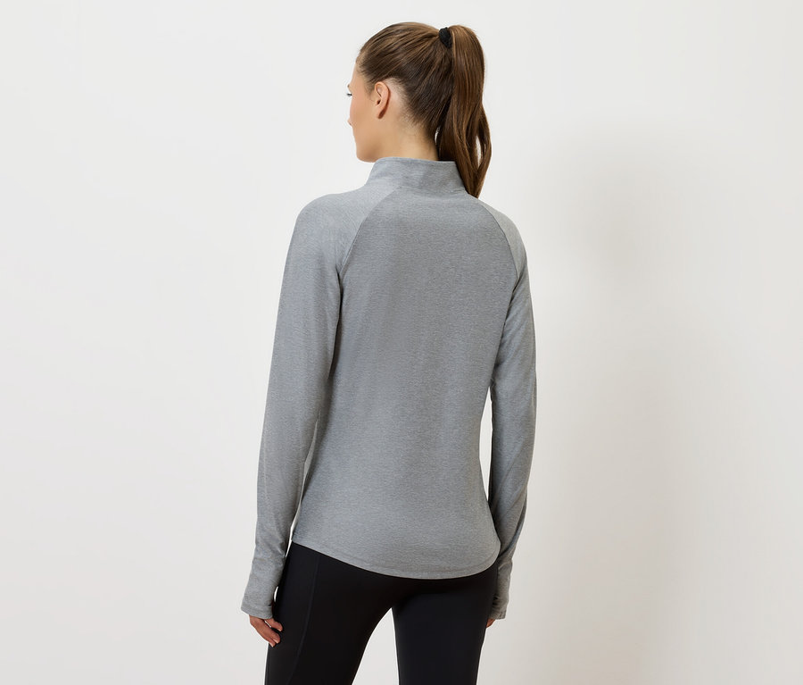 Une femme, dos à la caméra, porte un haut gris à manches longues et un pantalon noir.