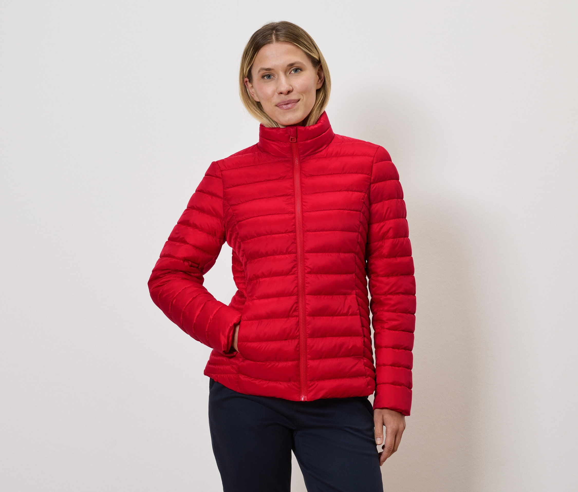 Femme posant dans une veste matelassée rouge.