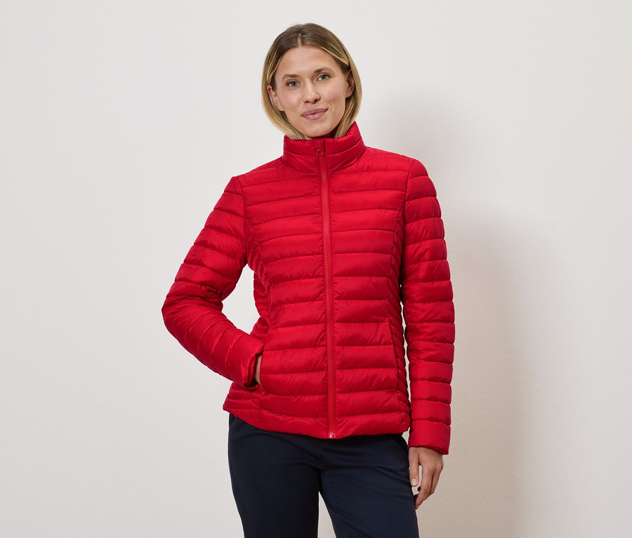 Femme posant dans une veste matelassée rouge.