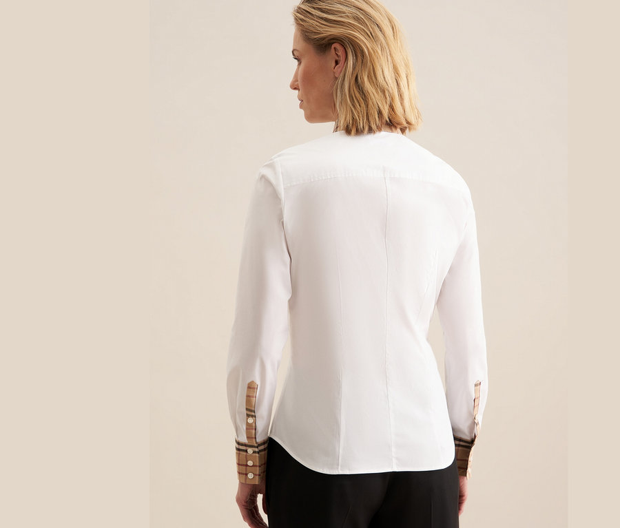 Vue arrière d'une femme portant une chemise en popeline blanche Seidensticker avec des détails à carreaux aux poignets.